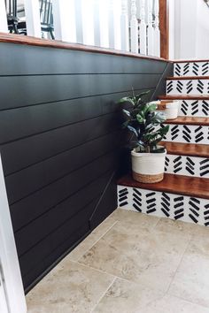 some potted plants are sitting on the steps in front of a black and white wall