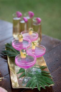 there are many glasses on the table with pink drinks in them and some green leaves