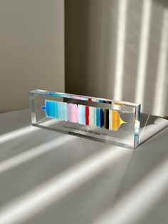 a glass box with some different colored paints in it's display stand on a table