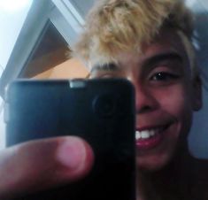 a young man taking a selfie in front of his cell phone with blonde hair