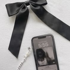 a cell phone with a black bow on it next to a lanyard and key chain