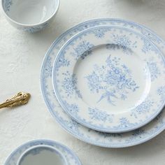 the blue and white china is set on the table with silverware in front of it