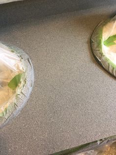 two pies sitting on top of a counter covered in plastic