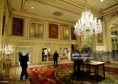 two men are standing in the lobby of a large building with chandeliers hanging from the ceiling