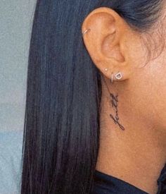 the back of a woman's head with a small tattoo on her left ear