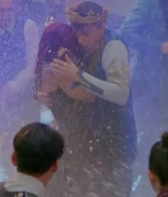 two people are hugging in the water fountain