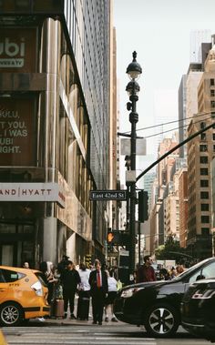 people crossing the street at an intersection in new york city, with taxis and taxi cabs