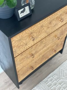 a black and wood dresser with some plants on top