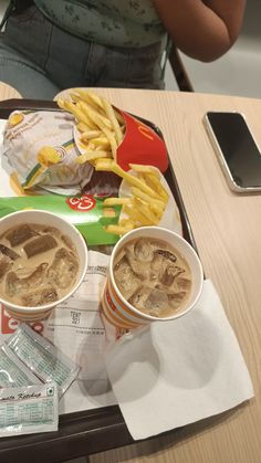 a tray with french fries, hotdogs and drink on it