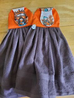 two children's dresses with cartoon characters on them sitting on a wooden floor next to each other