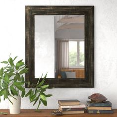 a mirror sitting on top of a wooden table next to a potted green plant