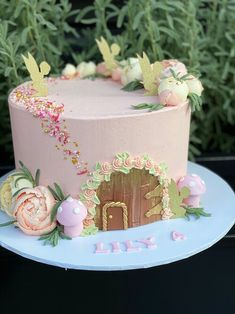 there is a pink cake with flowers on the top, and a fairy door in the middle