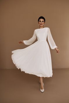 a woman in a white dress posing for the camera with her arms outstretched and legs spread out