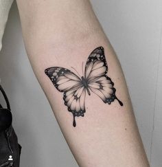 a black and white butterfly tattoo on the arm