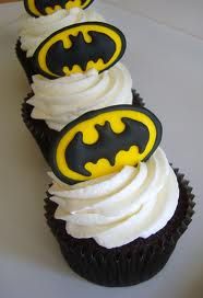 three cupcakes with white frosting and black icing decorated to look like batman's