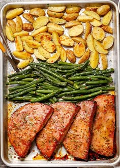 a pan filled with fish, potatoes and green beans next to a bowl of dipping sauce