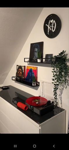 there are two shelves on the wall with pictures and other items in them, along with a record player