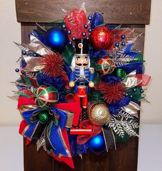 a christmas wreath with a nutcracker and decorations on it in front of a wooden sign