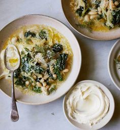 three bowls of soup with spinach, white beans and sour cream on the side