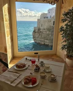 the table is set for breakfast by the window overlooking the water and cliffs in the distance