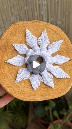 a hand holding a wooden object with white flowers on it's center and an arrow in the middle