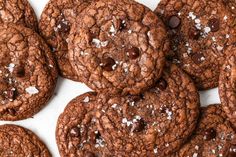 a pile of chocolate cookies with sea salt sprinkled all over them on a white surface