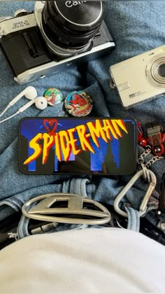 there is a camera and some other items on top of someone's jeans with the name spider man