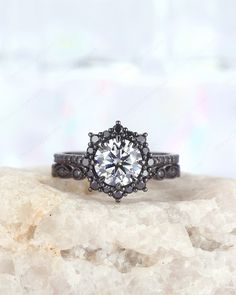 a black and white diamond ring sitting on top of a rock