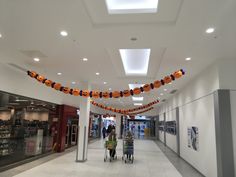 an empty shopping mall with people walking down the hall and decorations hanging from the ceiling