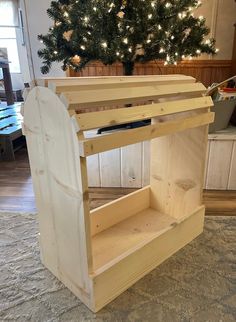 a wooden shelf sitting on top of a carpeted floor next to a christmas tree