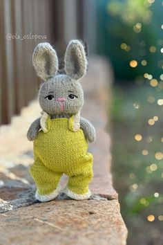 a knitted bunny doll sitting on top of a brick wall