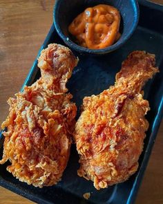 two fried chicken wings with dipping sauce on the side