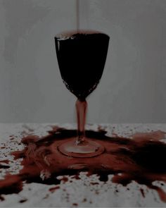 a wine glass sitting on top of a table covered in spilled red and white liquid