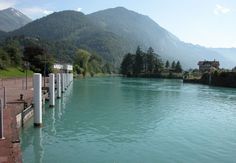 a body of water surrounded by trees and mountains in the distance with buildings on either side