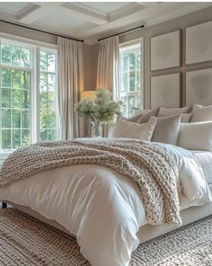 a large bed sitting in a bedroom next to two windows and a rug on the floor