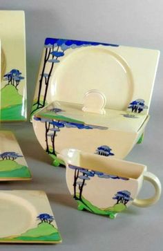 a set of four dinnerware with blue trees on the front and green grass on the back