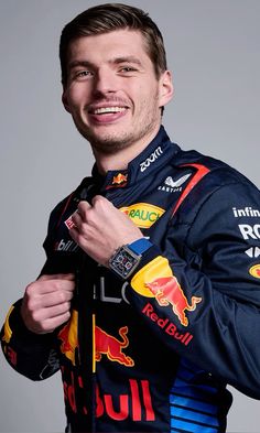 a man in a red bull racing suit is posing for a photo with his hands on his chest