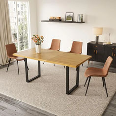 a dining room table with four chairs and a vase on the rug in front of it