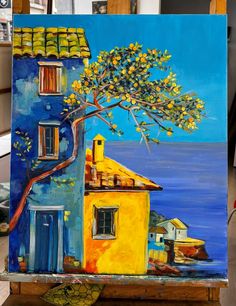 an easel with a painting of a house and tree on it