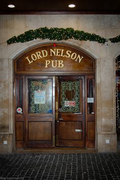 the front entrance to lord nelson pub with christmas decorations on the wall and lights hanging above it