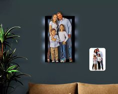 an image of a family hanging on the wall next to a couch and potted plant