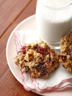 three cookies on a plate next to a glass of milk