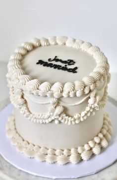 a three tiered cake with white frosting and black lettering on top, sitting on a plate