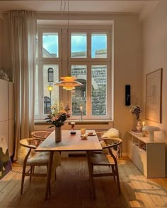 a dining room with a table and chairs in front of a large window that looks out onto the street