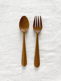 two wooden utensils sitting next to each other on top of a white cloth