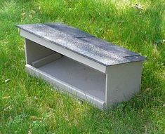 a concrete bench sitting on top of a lush green field next to a tree and grass covered ground