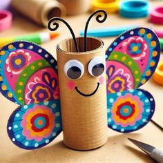 a toilet paper roll with a butterfly on it and some crayons in the background