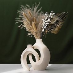 a white vase with some dried plants in it