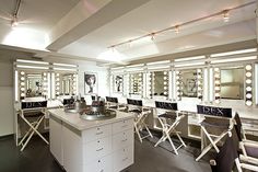 a room filled with lots of white chairs and vanity mirrors on the wall next to each other