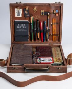 an open briefcase filled with lots of writing and office supplies on top of a white table